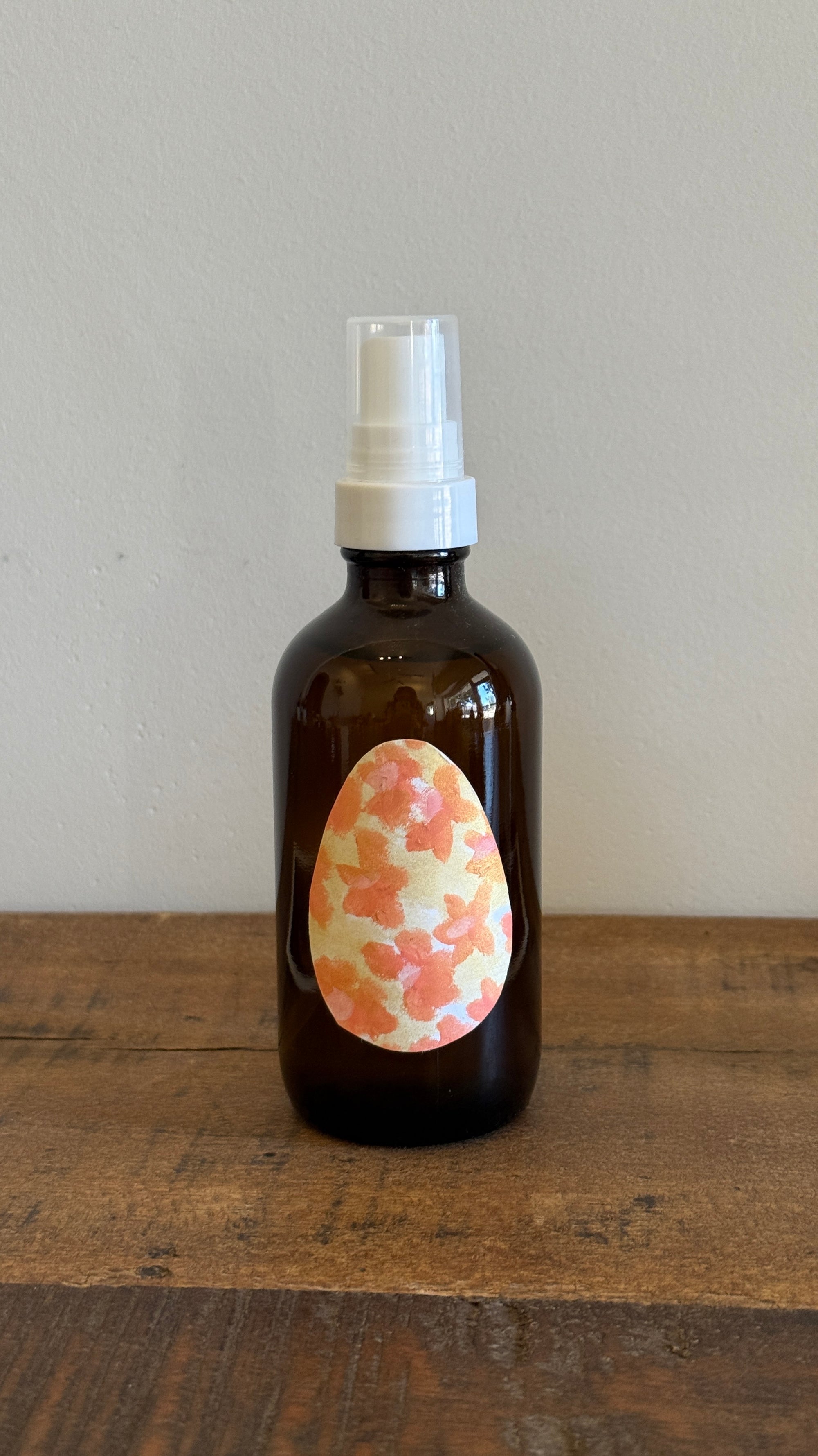 Brown glass bottle with floral label on a wooden surface